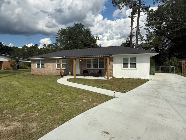 A residential house with a covered patio, a lawn, and a driveway.