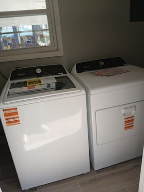 To frontbetjente Whirlpool vaskemaskiner med vejledningsskilte og et vindue over dem.