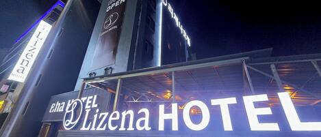 A hotel sign with 'EL Lizena HOTEL' and a tower with 'GRAND OPEN' signage.