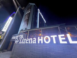Un letrero de hotel con la leyenda 'EL Lizena HOTEL' y una torre que muestra la señalización 'GRAND OPEN'.