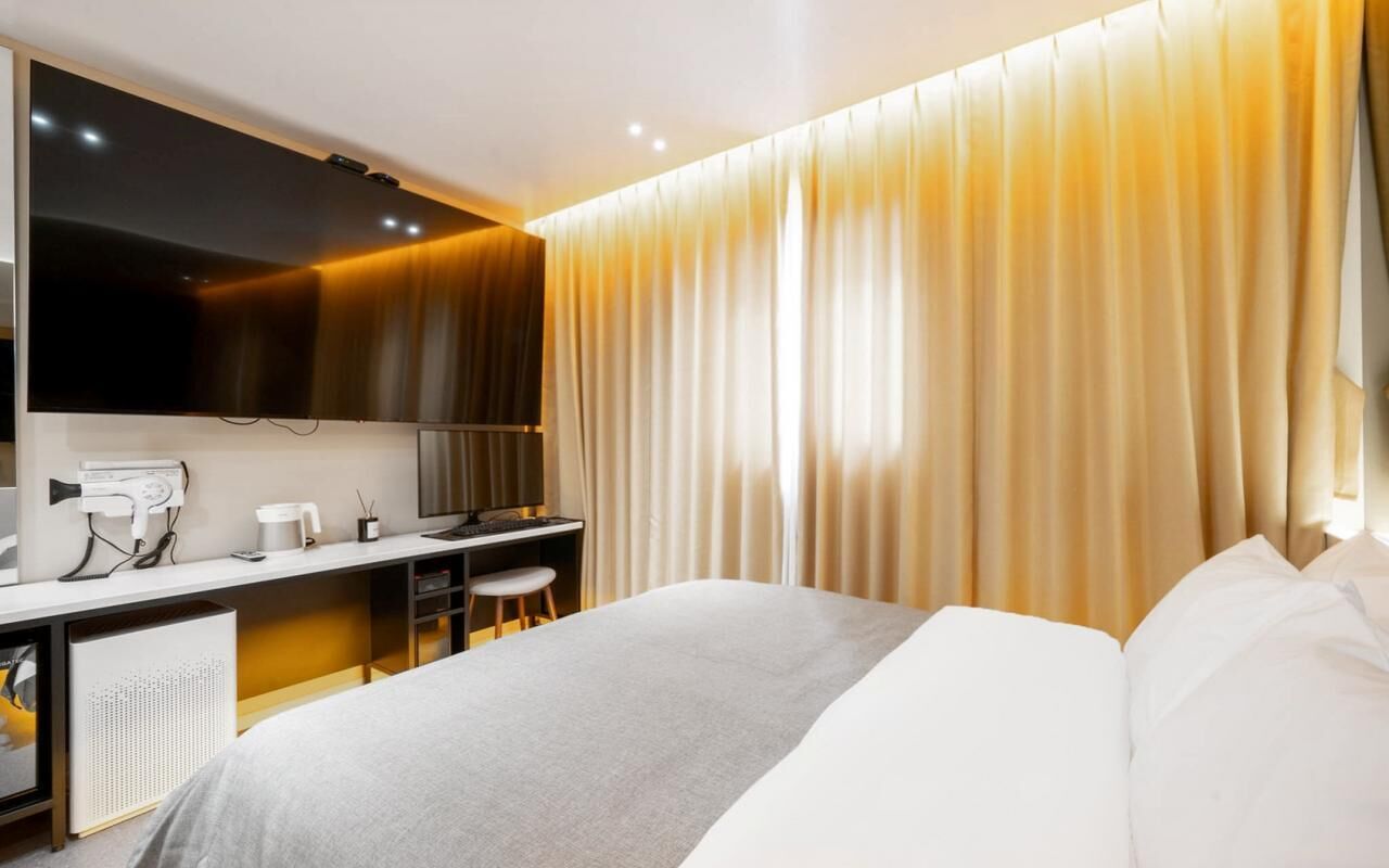 Quarto de hotel moderno com cama, escrivaninha e um espelho grande.