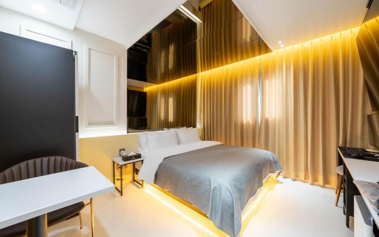 A modern hotel room with a bed, a desk, and a chair.