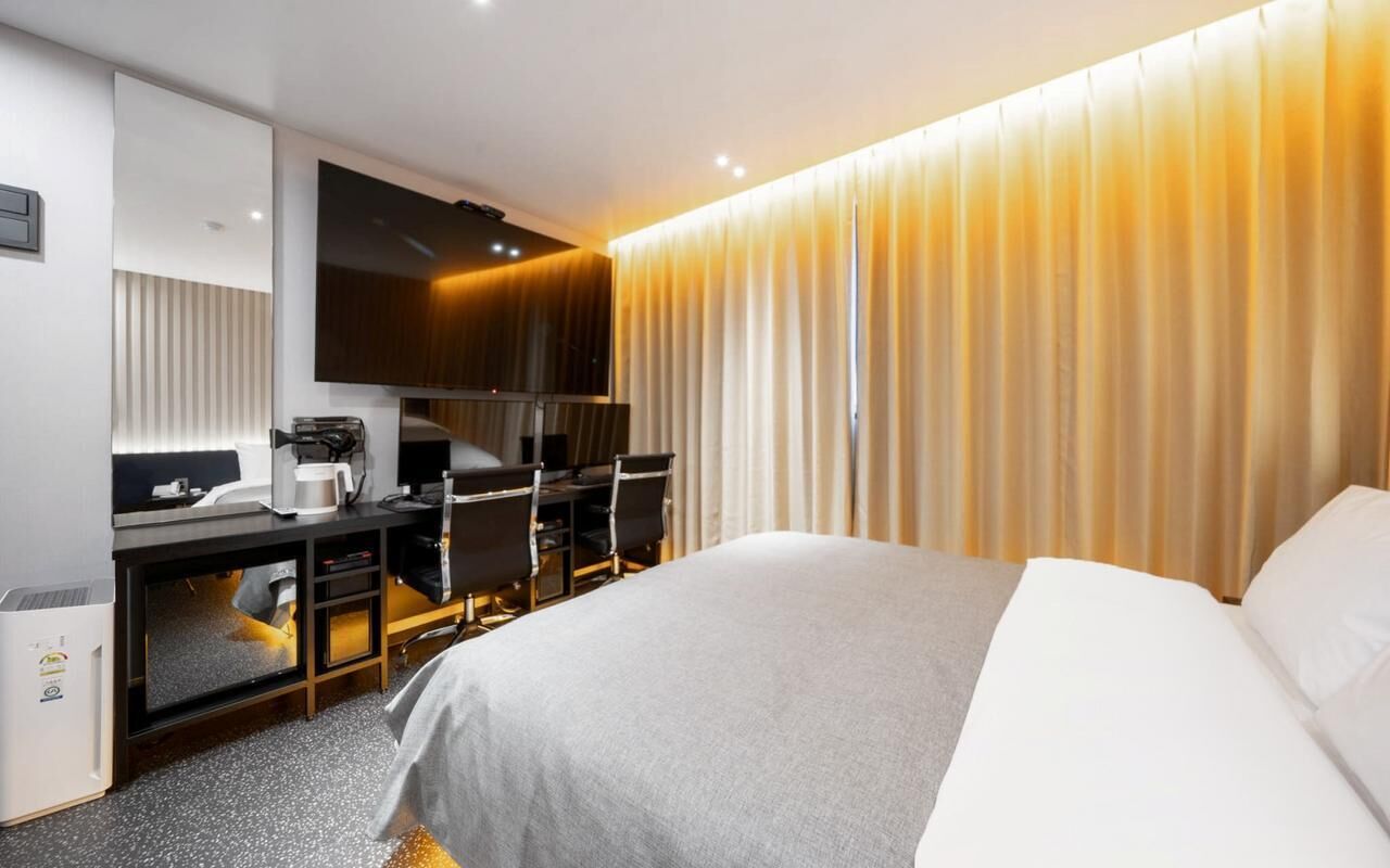 A hotel room with a bed, desk, chair, and a television.