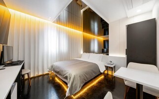 Una habitación de hotel moderna con una cama grande, un escritorio, una silla y una mesita de noche.