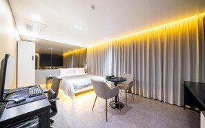 A hotel room with a bed, desk, chairs, and a TV. - Lizena HOTEL (Asan)