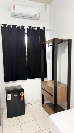 A room with a bunk bed, a black refrigerator, a window with black curtains, and an air conditioning unit on the wall. - Pousada Gente Feliz (Apiacás)