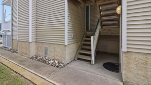 A building with beige siding, a wooden staircase, and a metal door. - Pet Friendly/ Top-Floor 3BR Retreat -Near Beach & 34th St (Ocean City)
