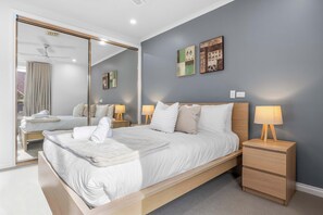 Un dormitorio moderno con una cama grande, mesitas de noche, un espejo y obras de arte en la pared.