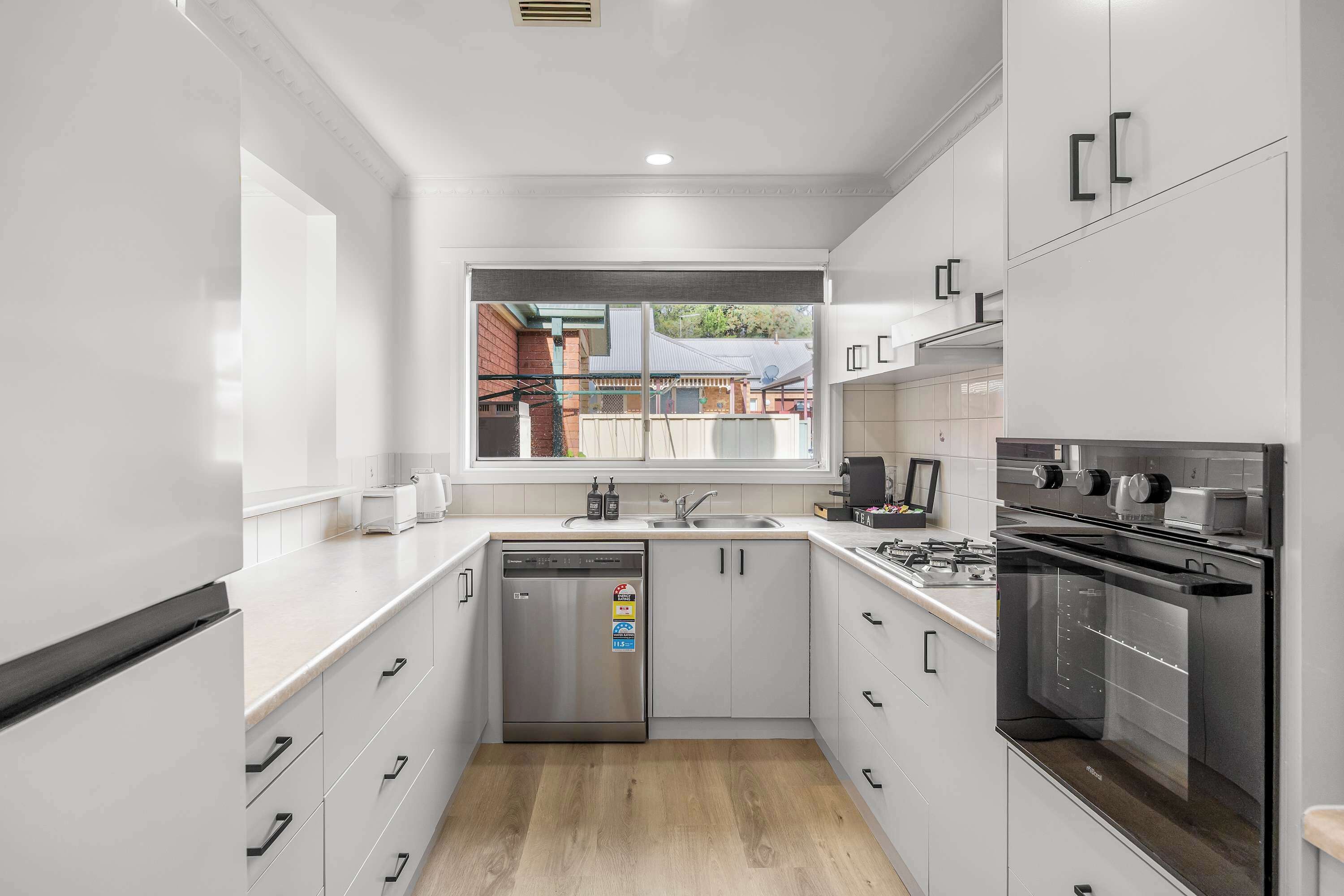 A modern kitchen with stainless steel appliances, a dishwasher, and a window overlooking a residential area.