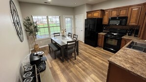A modern kitchen with wooden cabinets, a black refrigerator, a stove, and a dining area with a table and chairs. - Convenient Central Ky home in Georgetown, 11 mins to Horse Park (Georgetown)