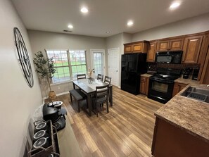 A modern kitchen with wooden cabinets, a black refrigerator, a stove, and a dining area with a table and chairs. - Convenient Central Ky home in Georgetown, 11 mins to Horse Park (Georgetown)