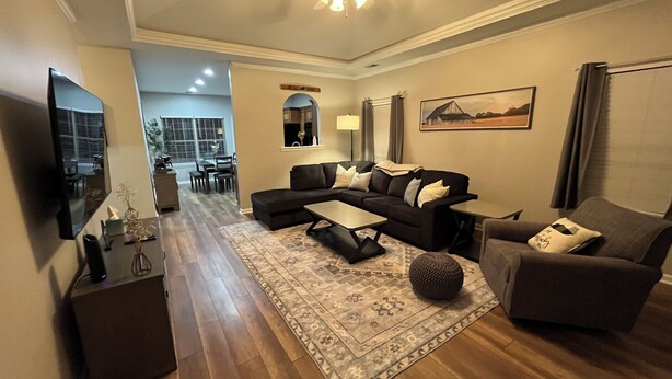 A modern living room with a sectional sofa, a coffee table, and a TV. There is a dining area in the background with a table and chairs. - Convenient Central Ky home in Georgetown, 11 mins to Horse Park (Georgetown)
