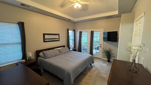A bedroom with a bed, a ceiling fan, a TV mounted on the wall, and a door leading to an outdoor area. - Convenient Central Ky home in Georgetown, 11 mins to Horse Park (Georgetown)