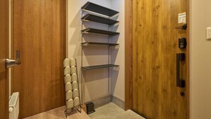 A corner of a room with wooden doors, a radiator, and a set of shelves against the wall. - Niseko Town Retreat Amber (Abuta-gun, Kutchan-cho)
