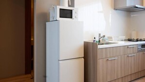 A kitchen with a white refrigerator, microwave, and stove, wooden cabinets, and a sink. - Niseko Town Retreat Amber (Abuta-gun, Kutchan-cho)