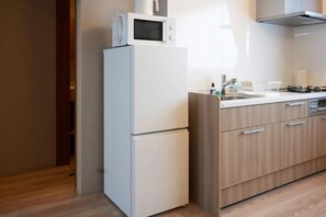 A kitchen with a white refrigerator, microwave, and stove, wooden cabinets, and a sink.