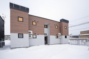 A building with a brick facade, multiple air conditioning units, and a gated entrance.