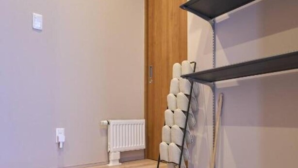 A room with a wooden floor, a radiator, a white radiator, a black shelf, and a white door. - Niseko Town Retreat Amber (Abuta-gun, Kutchan-cho)