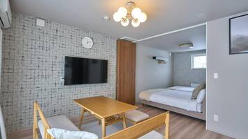 Una habitación moderna con pared de ladrillo, un televisor de pantalla plana, una mesa de madera con bancos, una cama y una ventana.