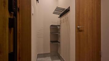 En smal gang med en trædør til højre, et vægmonteret håndklædestativ og et lille reolsystem.