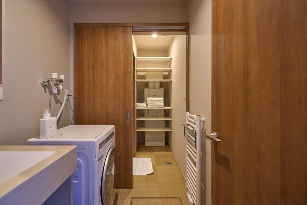 Un cuarto de lavandería con lavadora, secadora y repisas con toallas.