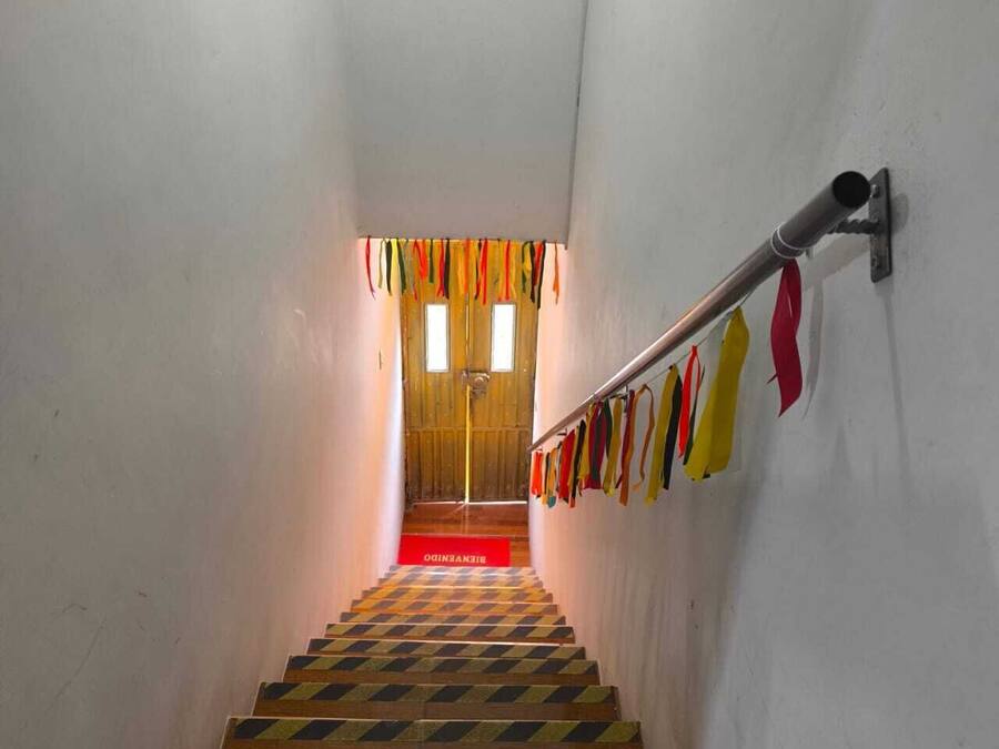 A staircase with a checkered floor pattern, a handrail, and colorful ribbons hanging from the wall.