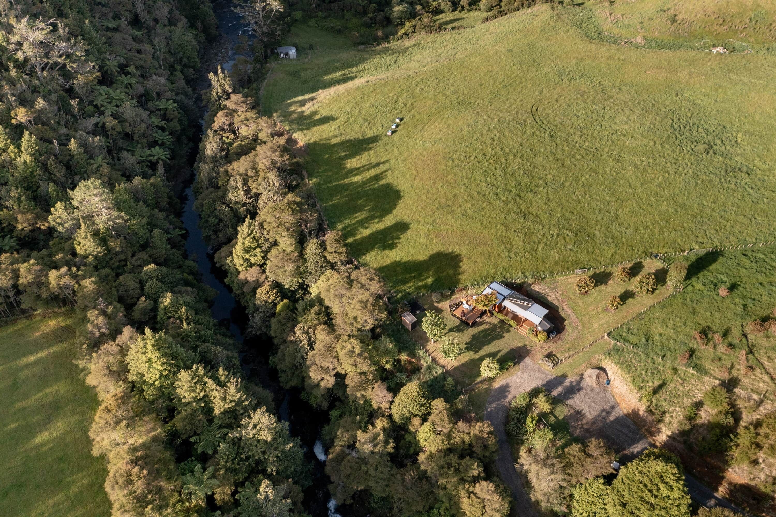 Eine Luftaufnahme eines Grundstücks mit einem Haus, einem eingezäunten Garten und einem Fluss.