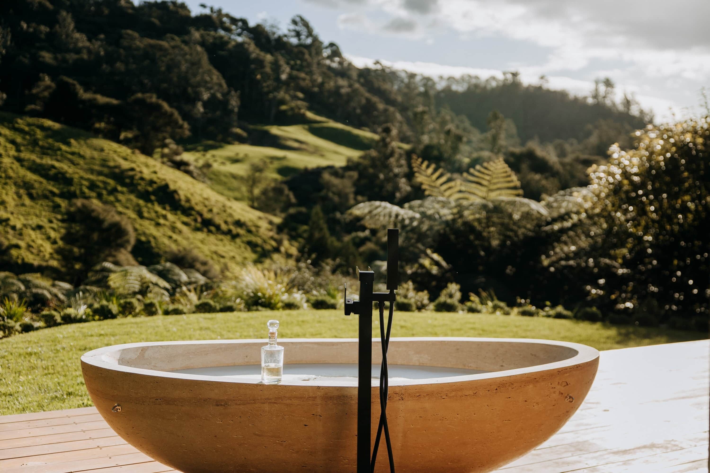 A large, round, outdoor water feature with a glass container in the center, surrounded by a wooden deck.
