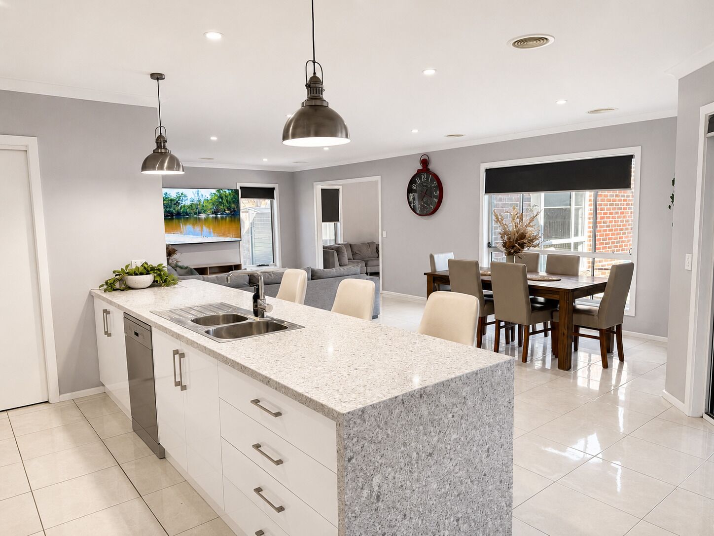 A modern kitchen with granite countertops, a built-in dishwasher, and pendant lighting.