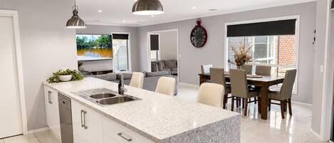A modern kitchen with granite countertops, a built-in dishwasher, and pendant lighting.
