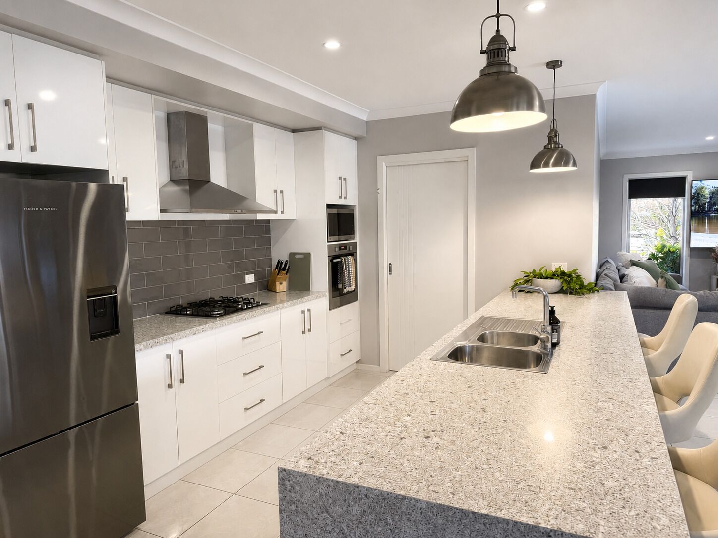 A modern kitchen with white cabinets, a stainless steel refrigerator, a granite countertop, and a built-in oven.