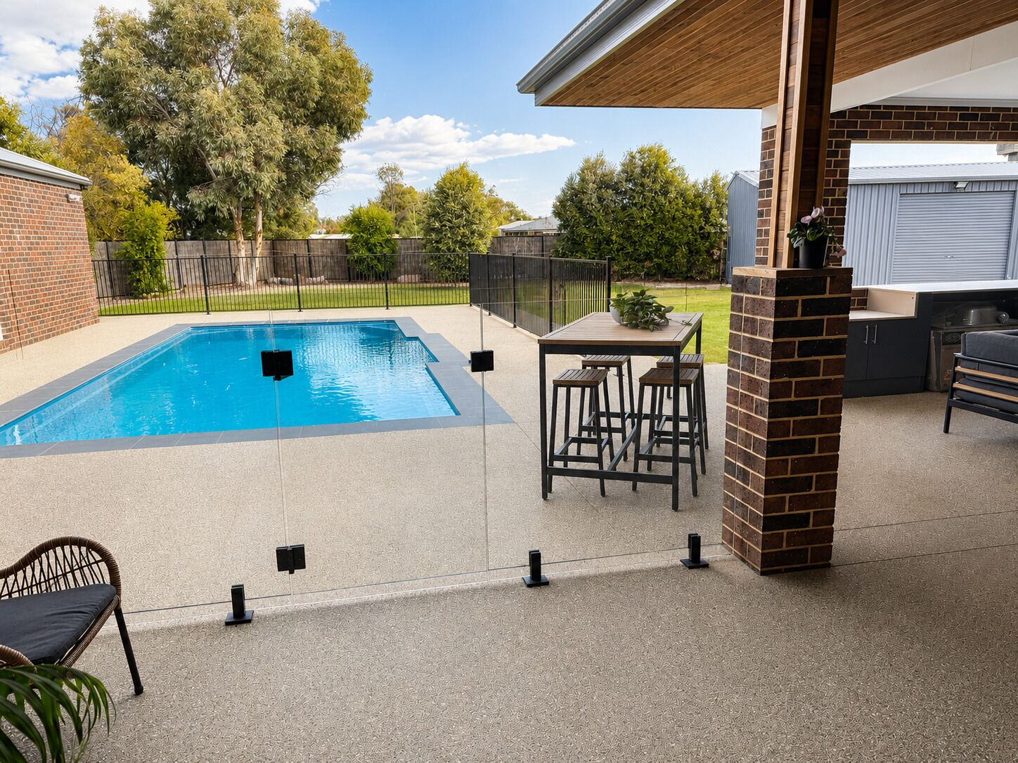 A backyard with a swimming pool, a barbecue area, and outdoor seating.