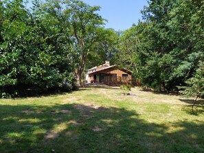 A rustic cabin surrounded by dense trees and a grassy yard. - My Country House (EUGENIE LES BAINS)