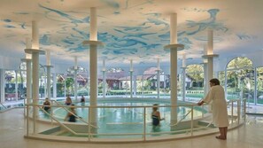 An indoor swimming pool with a unique ceiling design, surrounded by large windows. - My Country House (EUGENIE LES BAINS)