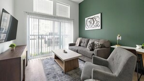 Una sala de estar moderna con sofá, sillón, mesa de centro y televisor sobre un mueble.