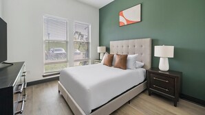 A hotel room with a bed, bedside tables, a TV, and a window with blinds. - Landing | Stunning 1BD (Nashville)
