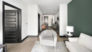 Un salon moderne avec un canapé, un fauteuil et, au fond, un coin repas.