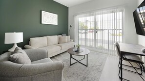 Ein modernes Wohnzimmer mit einer Couch, einem Sessel, einem Couchtisch und einem Essbereich mit Tisch und Stühlen.