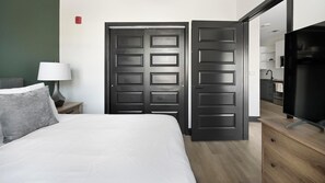 A hotel room with a bed, a nightstand, a lamp, a TV, and a wardrobe. - Landing | Stunning 1BD (Nashville)