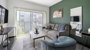 Ein modernes Wohnzimmer mit einer Couch, einem Couchtisch, einem Fernseher und einem Bild an der Wand.