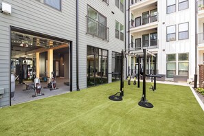 A gym area with exercise equipment and a building exterior. - Landing | Beautiful 1BD (Nashville)