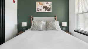 A bed with a geometric patterned headboard, two bedside lamps, and a wall art piece above. - Landing | Chic 1BD - One Bedroom Apartment, Sleeps 2 (Nashville)