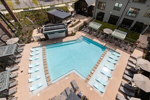 Ein Pool auf dem Dach mit Liegestühlen und einem kleinen Gebäude mit geneigtem Dach.