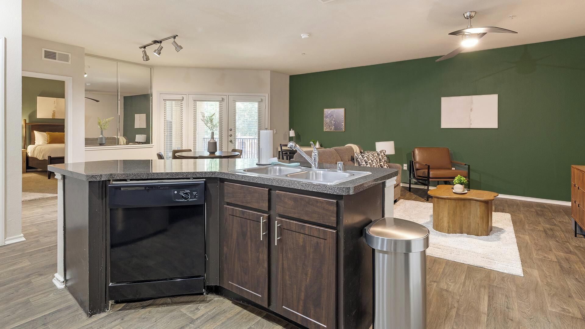 A modern kitchen with dark cabinetry, a dishwasher, and a sink.