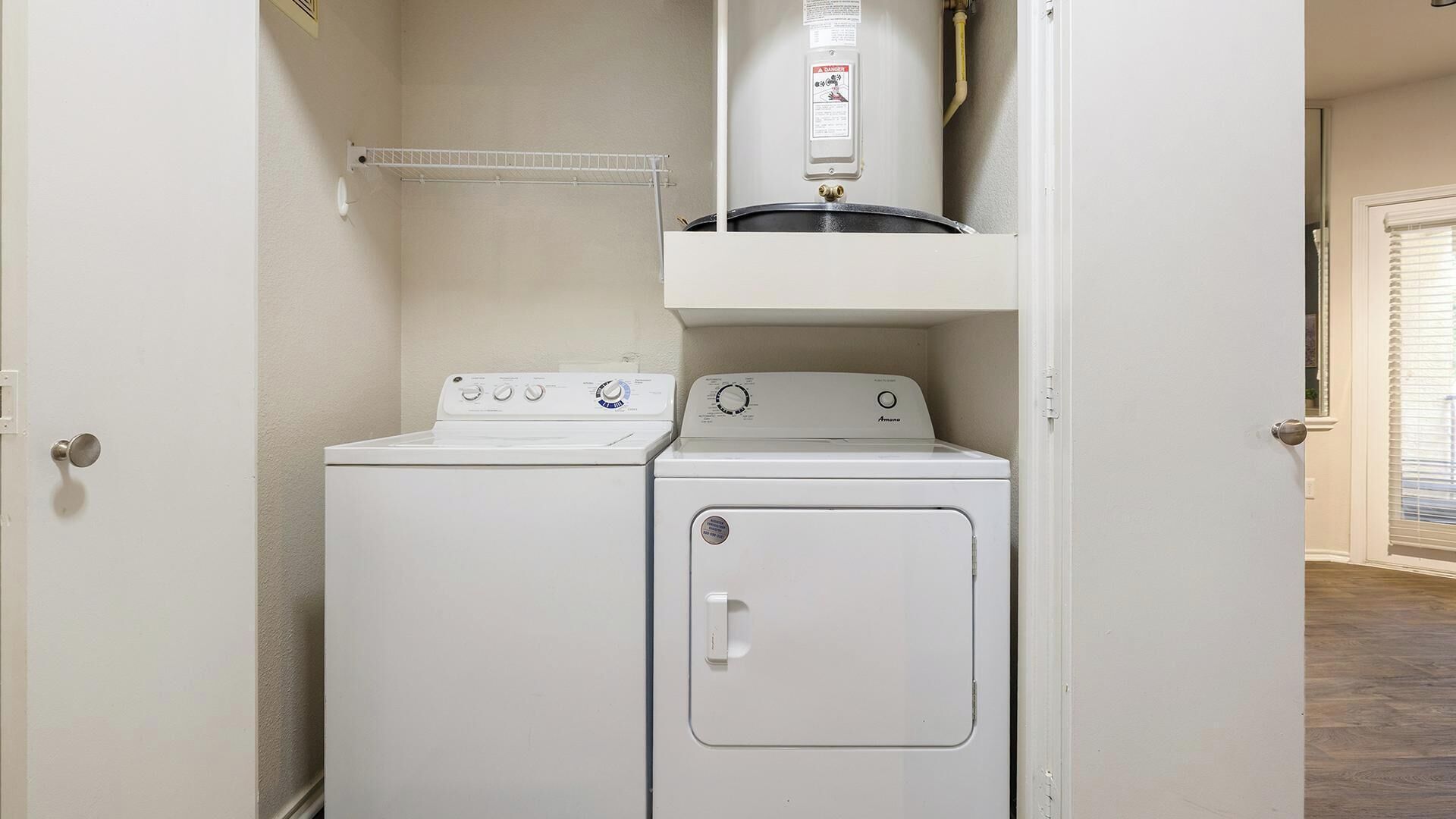 A laundry room with a washer and dryer, a water heater, and a shelf above the dryer.