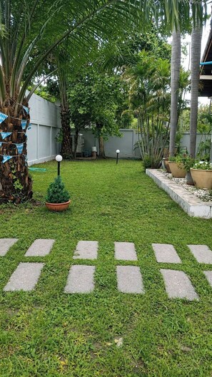 A well-maintained garden with a lawn, stepping stones, and various plants. - Luxury 3-bedroom villa with private pool in Pattaya (Muang Pattaya)