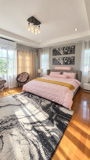 A bedroom with a bed, a chair, a rug, and artwork on the wall. - Luxury 3-bedroom villa with private pool in Pattaya (Muang Pattaya)