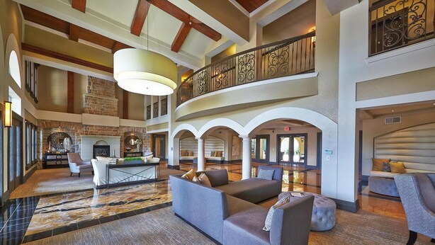 Een ruime lobby met een open haard, zithoek en een tweede verdieping balkon met decoratieve balustrades.