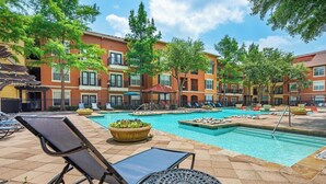 A pool area with lounge chairs, a small pool, and a building with multiple balconies. - Landing | Incredible 1BD, Clubhouse (Irving)
