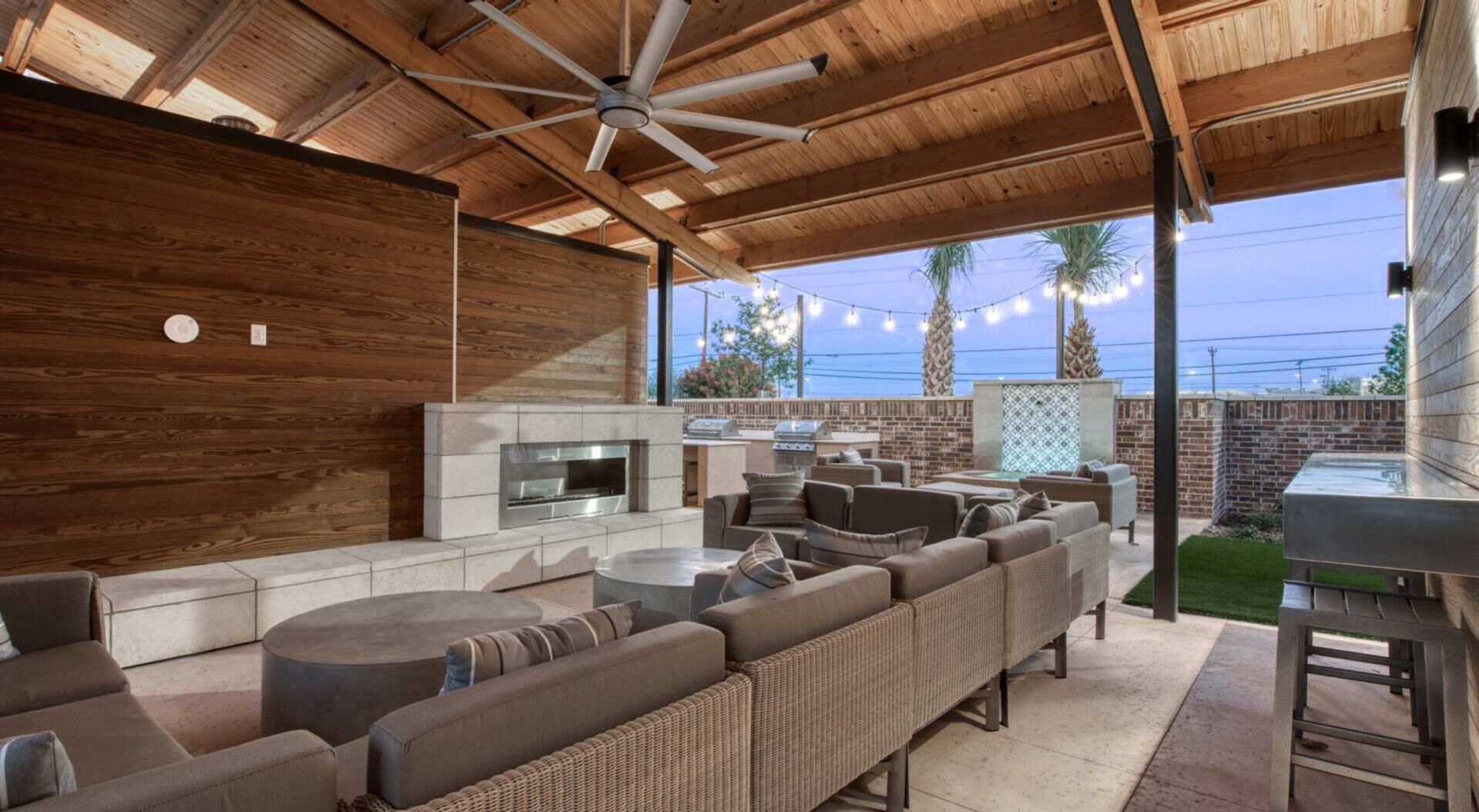 Une terrasse extérieure dotée d’un barbecue intégré, d’un espace salon et d’un ventilateur de plafond.